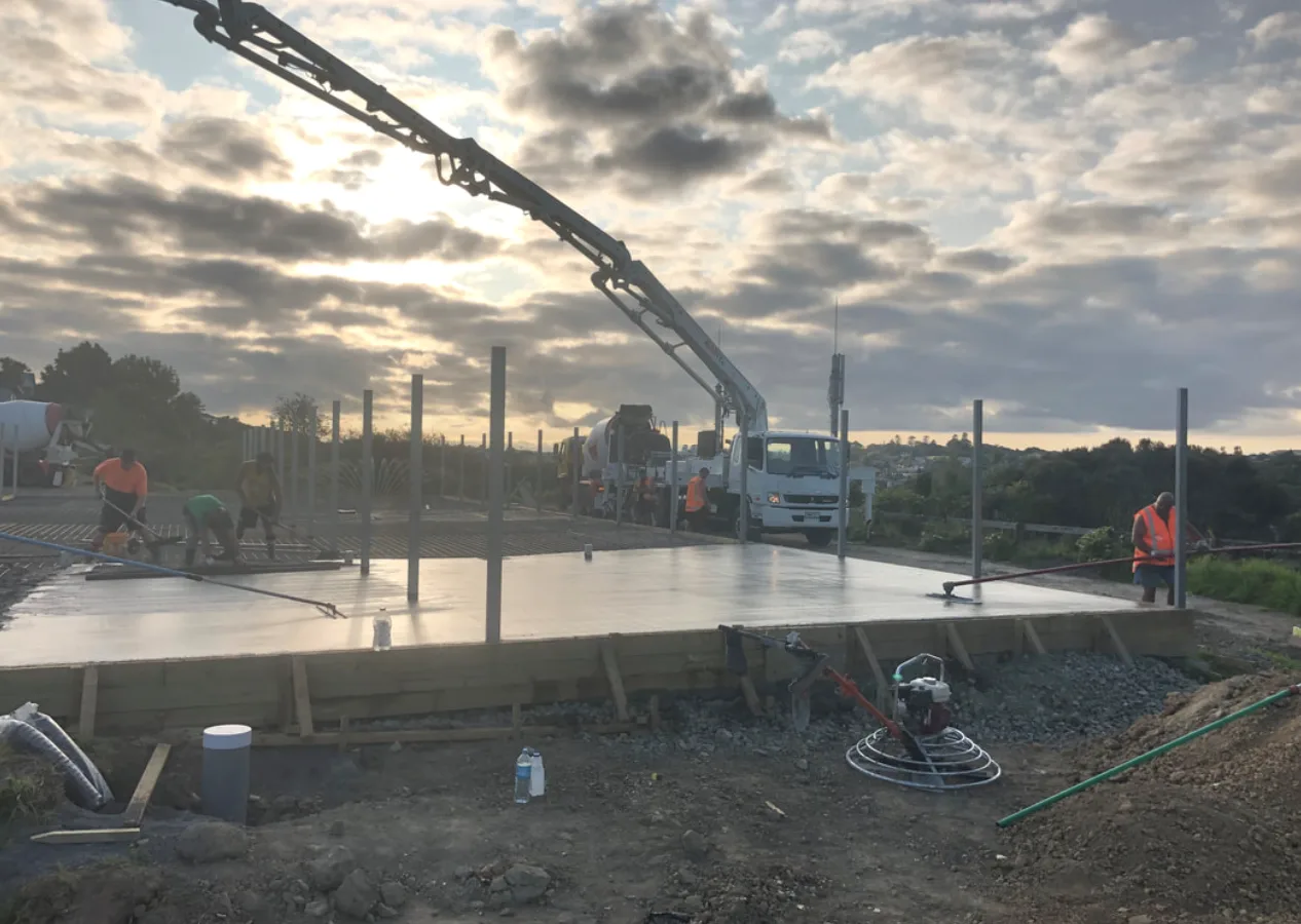 Concrete pump truck placing a large slab at dusk