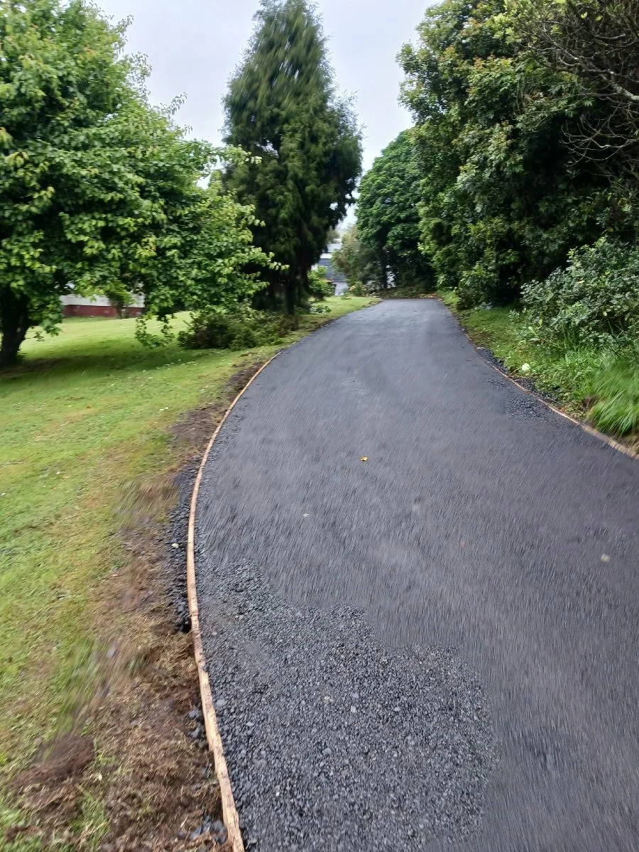 Recycled asphalt driveway running through lawn and mature trees