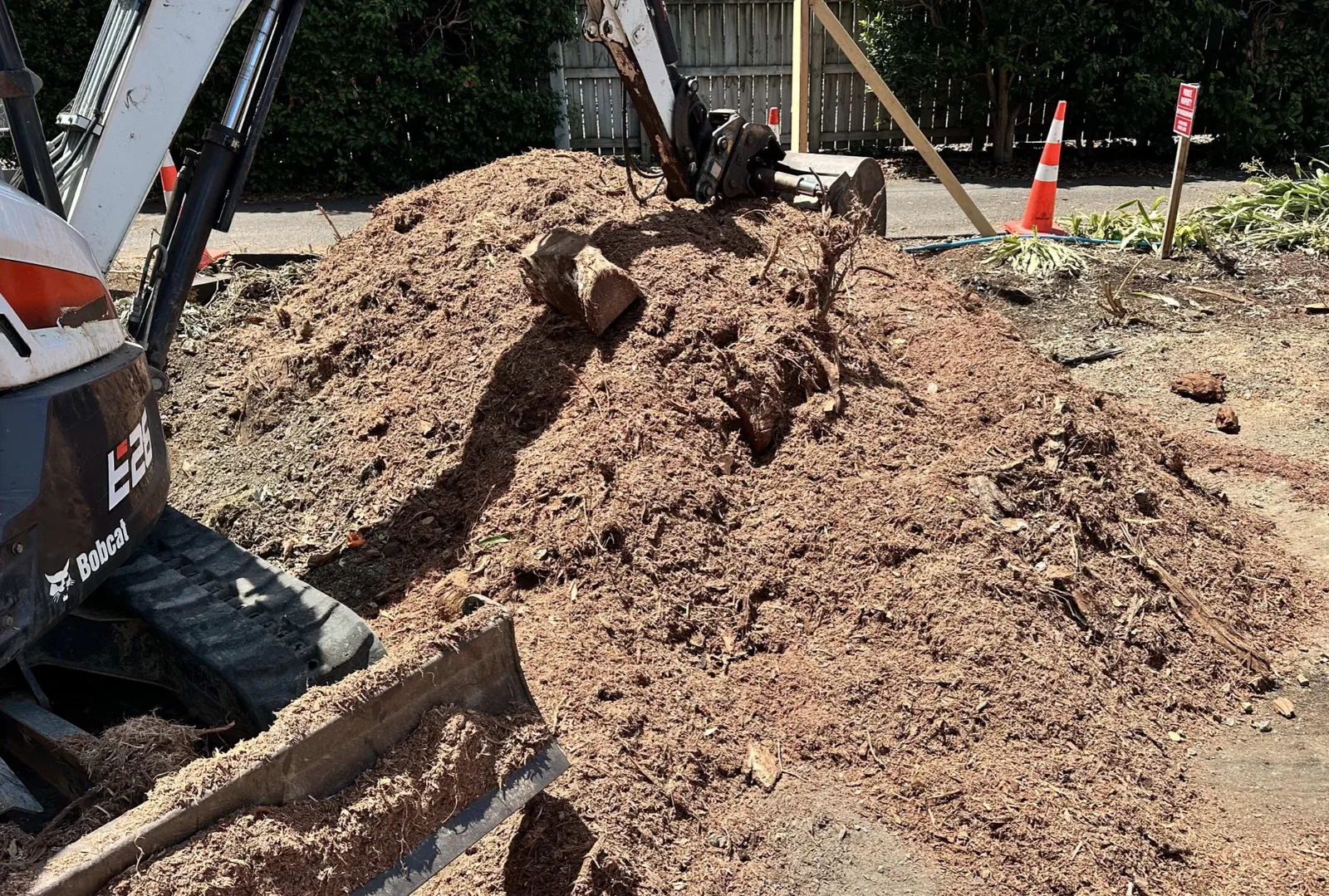 Excavator digging a trench beside a mound of excavated soil