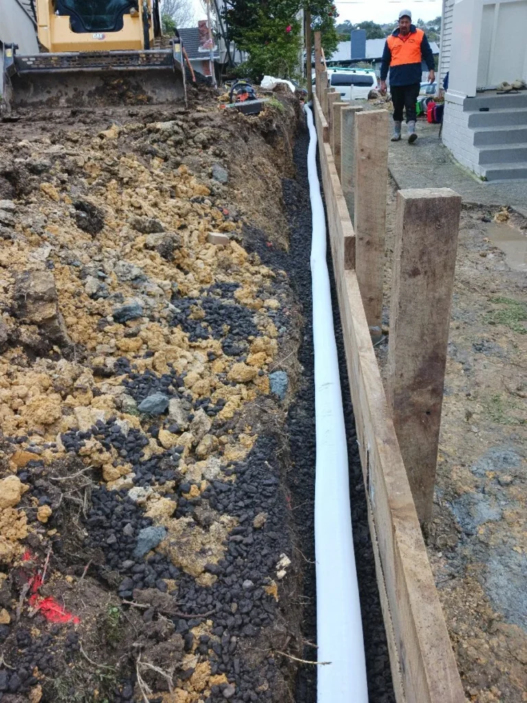 Drainage trench backfilled with drainage metal beside a house