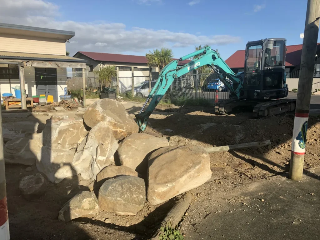 Excavator moving large rocks on a residential site